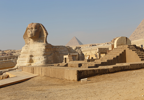 Egyptian sphinx and pyramids in the back in the desert near Cairo.