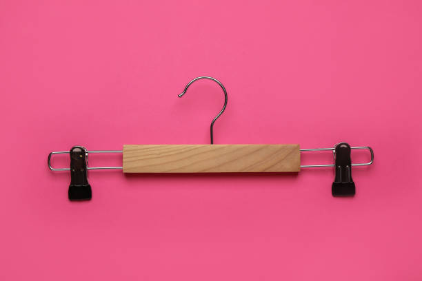 istock Empty wooden hanger with clips on pink background, top view 1442524969