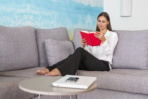 istock Happy young lady resting on sofa and reading book 1442525211