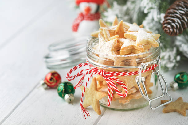 biscuits sablés de noël ou étoiles en pain d’épices avec ruban rouge, décoration festive, sapin, boules et guirlande lumineuse. cookies traditionnels allemands. traditions de célébration de noël culinaires familiales. - cookie christmas shortbread christmas tree photos et images de collection