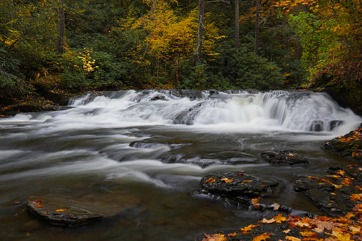 Motion-blurred water of Dingmans Creek surrounded by fall color in the Poconos on Pennsylvania