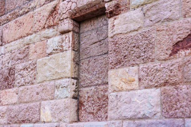 Bricked up window of an old ancient building with uneven stone wall close-up