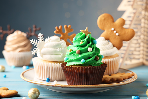 Different beautiful Christmas cupcakes on light blue wooden table