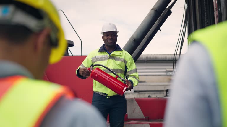 Male staff talking and demonstration how to use a fire extinguisher to Containers worker at Logistic container area company.