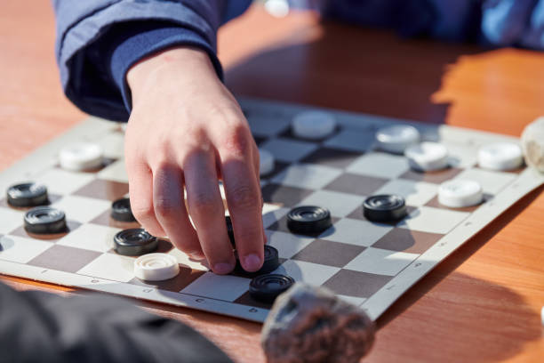 istock Outdoor draughts competition on paper checkerboard on table, close up players hands 1442548972
