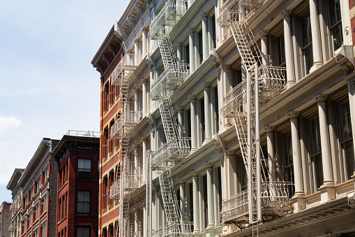 A row of beautiful old and colorful brick buildings with fire escapes in SoHo of New York City