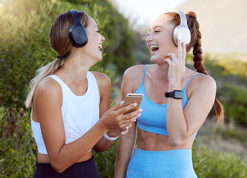 Fitness music, happy nature and friends listening to radio with phone while training in summer, smile for podcast during workout and motivation for gym. Women with funny audio during outdoor exercise