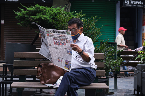 Gangtok, India, 21 June 2022, Middle-aged man reading newspaper at the side of the road.