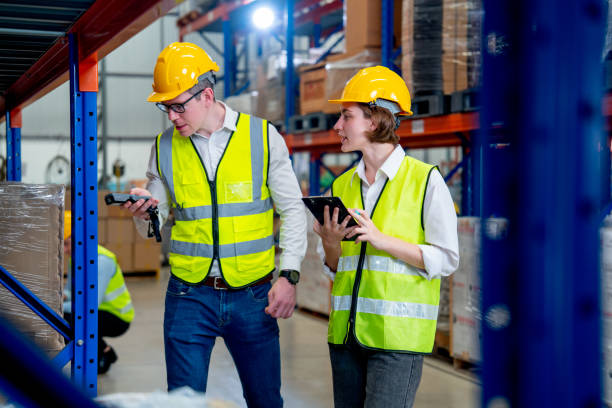 istock Professional warehouse worker man use barcode scanner to check the details of product on shelves and work with his co-worker woman and they ware safety protection in workplace. 1442557594