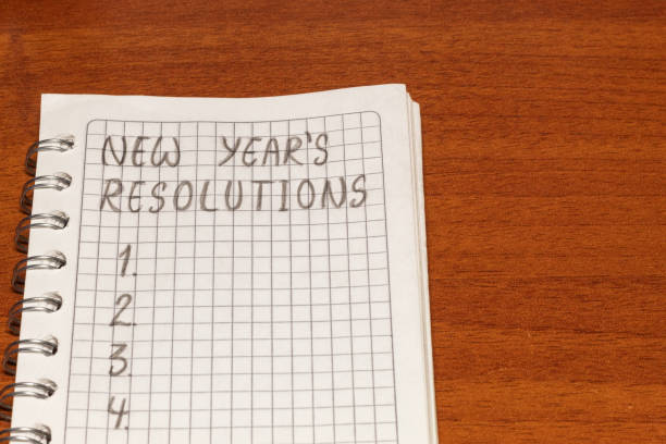 istock Close up of a notebook with space to write some new year's resolutions on a wooden table 1442558476