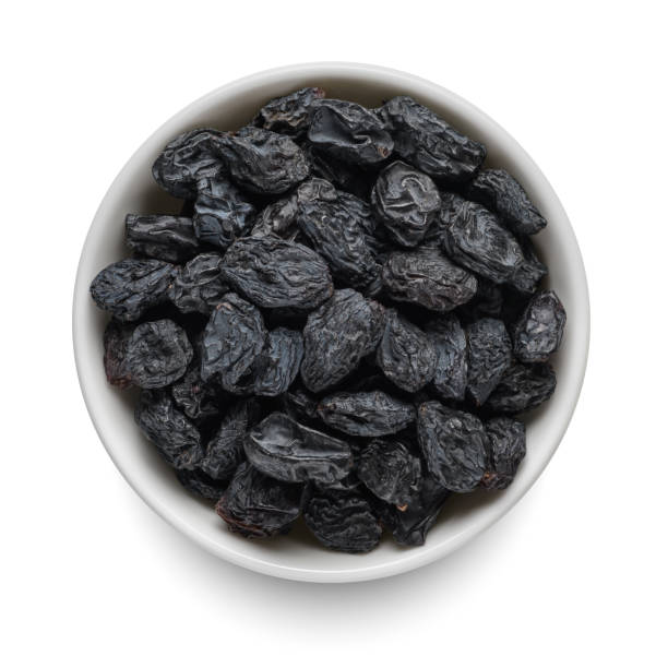 istock Black raisin in white bowl isolated on white. Top view. 1442561683