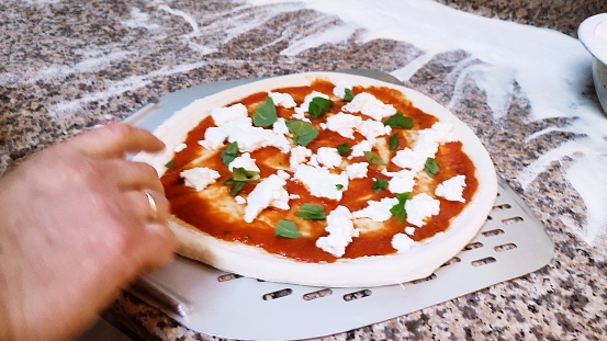 Making pizza margherita with salami in italian pizzeria, pizza peperoni
