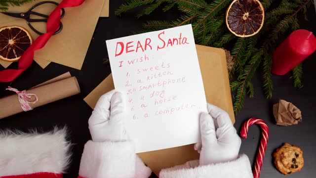 Santa Claus Reading Letters from Children on a Desk. Dear Santa. Top View of Jolly Father Hands Holding a Paper Page with Wish List. View from Above of Wood Table with Ornament, Christmas Decorations