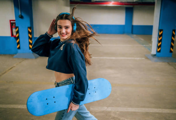 Smiling beautiful girl with her skateboard in the public parking garage
