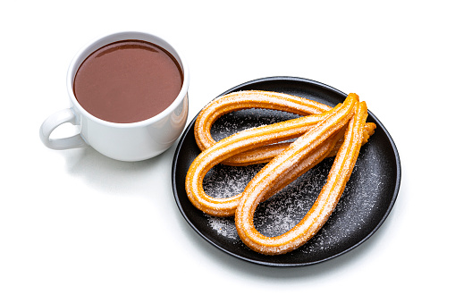 Sweet food: high angle view of fresh churros with sugar in a plate and hot chocolate mug isolated on white background. Dark chocolate bar and pieces complete the composition. High resolution 42Mp studio digital capture taken with Sony A7rII and Sony FE 90mm f2.8 macro G OSS lens