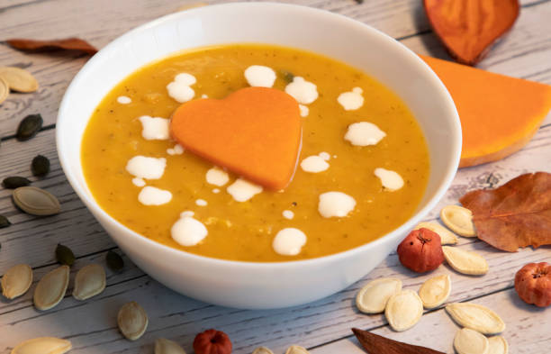 pumpkin cream soup in white bowl and seeds on a table stock photo
