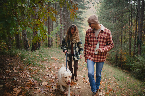 A couple in love enjoy hiking with their Labrador retriever dog