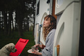istock A beautiful woman with curly hair is sitting in front of a camper enjoying nature 1442569678