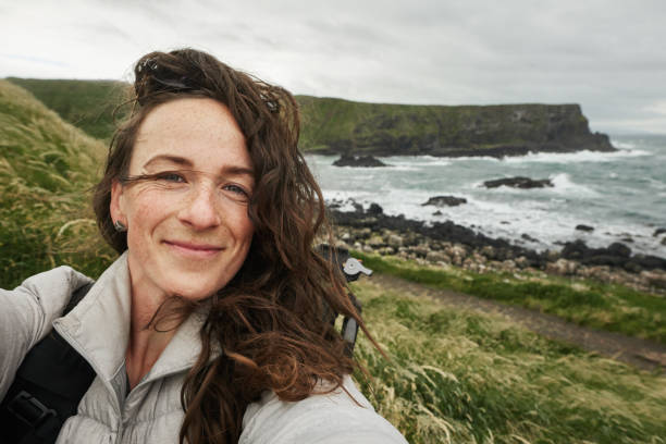 Woman smiling and taking selfies during a coastal hike
