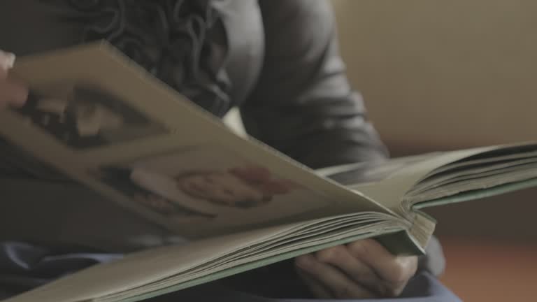 Human hand browsing old photo album pages. Woman is looking photo her family