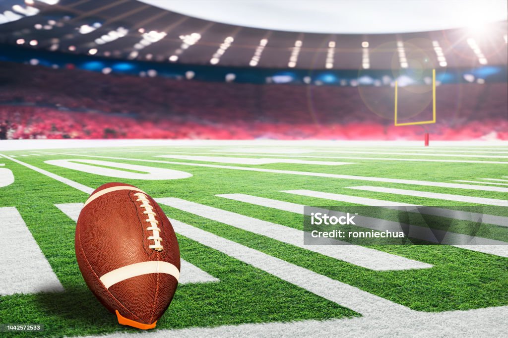 American football field goal post with ball on kicking tee American football stadium with goal post and ball on tee ready for field goal kick. Focus on foreground ball with shallow depth of field on background and copy space. American Football - Sport Stock Photo