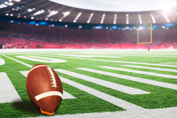 American football field goal post with ball on kicking tee American football stadium with goal post and ball on tee ready for field goal kick. Focus on foreground ball with shallow depth of field on background and copy space. american football field stock pictures, royalty-free photos & images