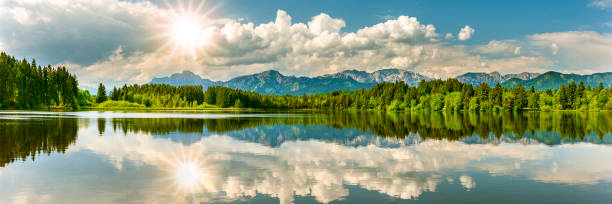 istock panoramic landscape with lake, mountain range and sun on sky 1442574176