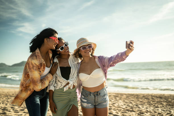 istock Young friends taking selfies or filming using mobile phone at the beach 1442574208
