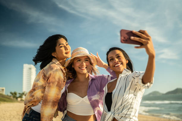 istock Young friends taking selfies or filming using mobile phone at the beach 1442574538