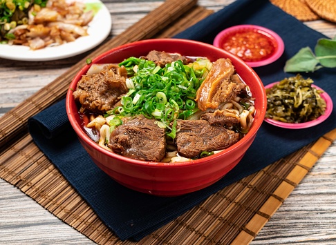beef noodles with green onion and chili sauce served in a bowl isolated on table top view of taiwanese food
