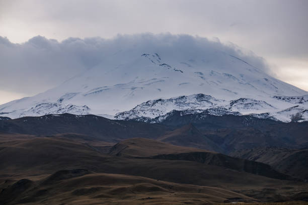 istock Snow and ice mountain Elbrus with a cloud at the top in cloudy weather with hills, a cool autumn day 1442576830