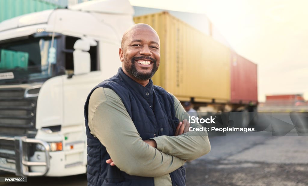 Delivery, container and happy truck driver moving industry cargo and freight at a shipping supply chain or warehouse. Smile, industrial and black man ready to transport ecommerce trade goods or stock Truck Driver Stock Photo