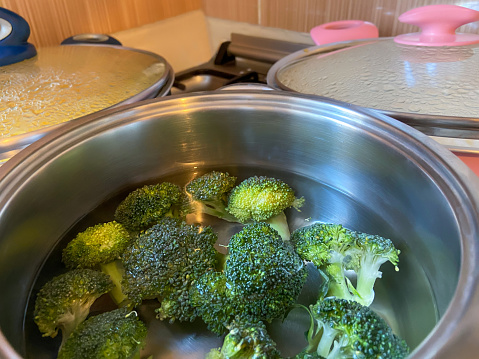 Broccoli boiling in the cooking pan on the stove top burner