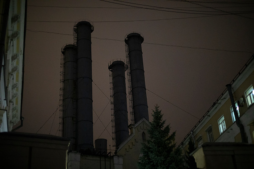 Factory at night. Pipes in dark. Industrial zone in city. Details of industrial architecture.