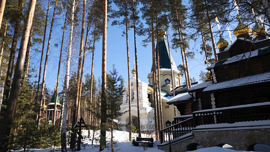 Old church tilt with white trees on hill in Russian winter season. Temple in the forest in winter.