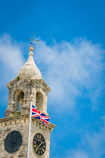The British Union Jack flies outside one of the twin clocktowers at the Royal Naval Dockyard where the clock indicates the next high water.