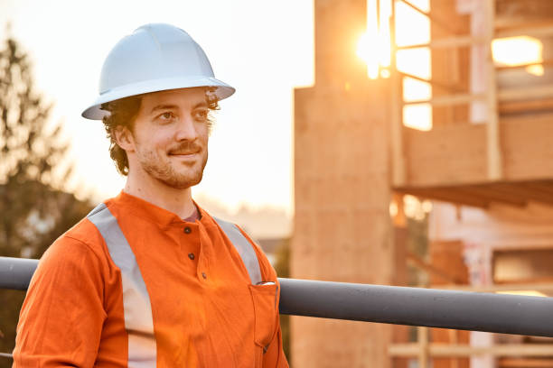 travailleur de la construction souriant debout sur un échafaudage sur un chantier de construction - building contractor flash photos et images de collection