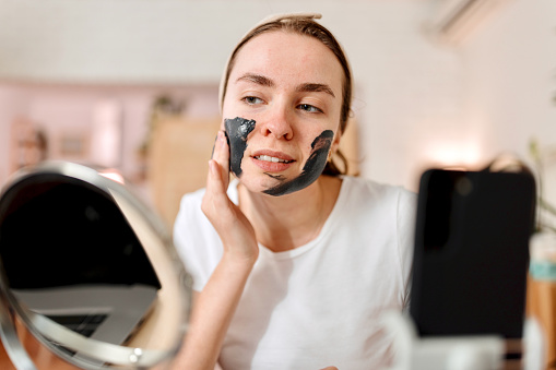 Acne-Prone Skin. Woman applying black face mask