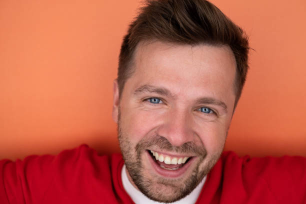 istock Yyoung man smiling while standing isolated on orange background 1442590686