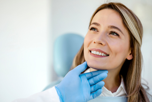 Satisfied young woman came to see the dentist. She sits in the dental chair. Cosmetic dentistry