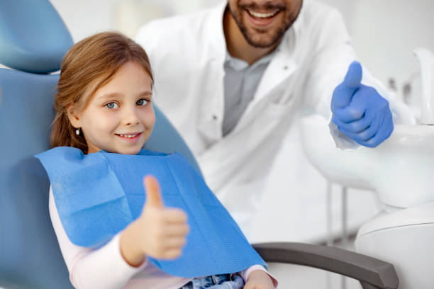 Child with Dentist Shows Thumb Up Little girl patient showing thumb-up approving pediatric dental service in modern clinic for children. Focus on happy smiling positively child. Good oral dent health pediatric dentistry stock pictures, royalty-free photos & images