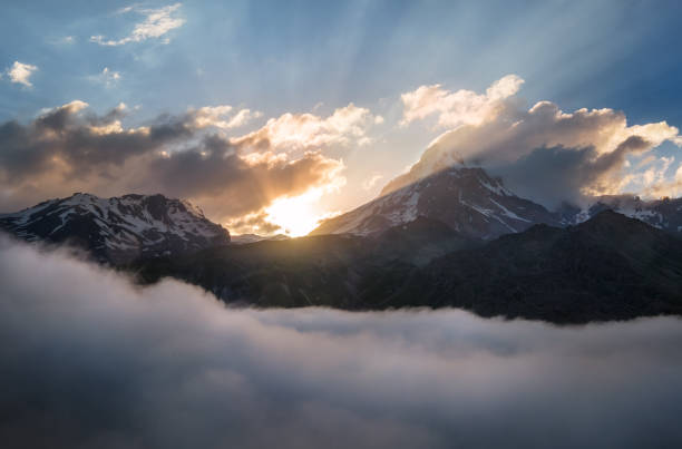 kazbek 5054m berg übersät mit sonnenuntergangslicht über den fließenden tief fließenden wolken, kaukasus, georgien - kazbek stock-fotos und bilder