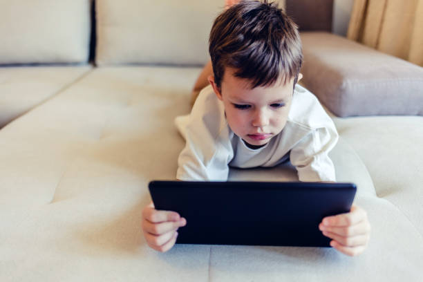 istock Boy playing with digital tablet. Cute little boy playing with a tablet pc on sofa at home. 1442596704