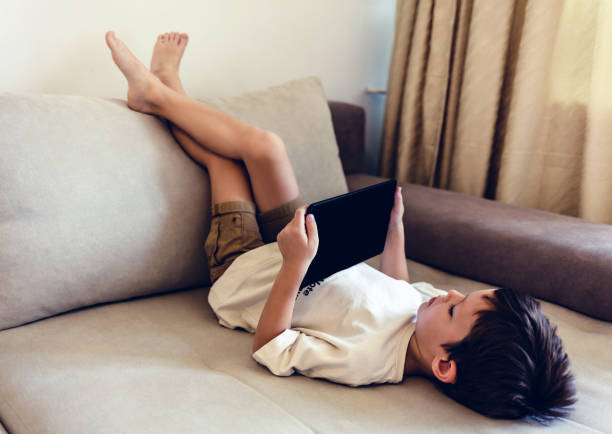 istock Boy playing with digital tablet. Cute little boy playing with a tablet pc on sofa at home. 1442596944