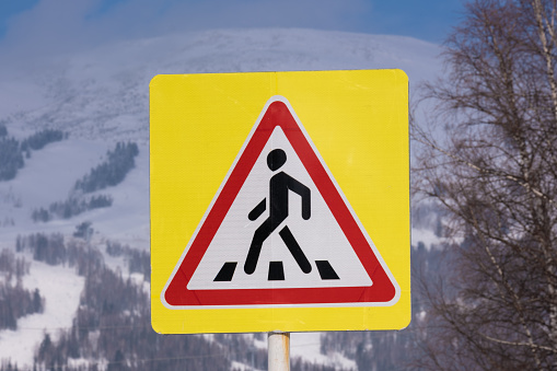 Pedestrian crossing and pedestrian sign. Mountains in the background. High quality photo