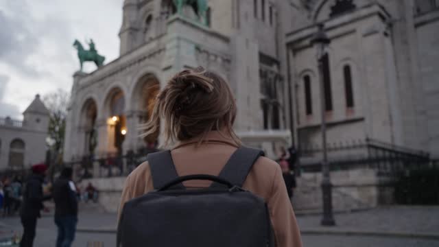 Female tourist admiring view of Basilica of the Sacred Heart in Paris, during sunset