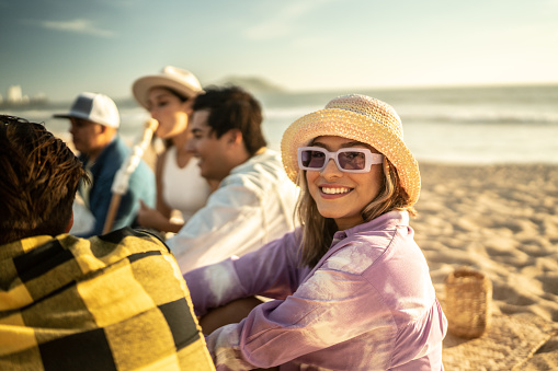 Portrait of young woman doing a picnic with friends at the beach