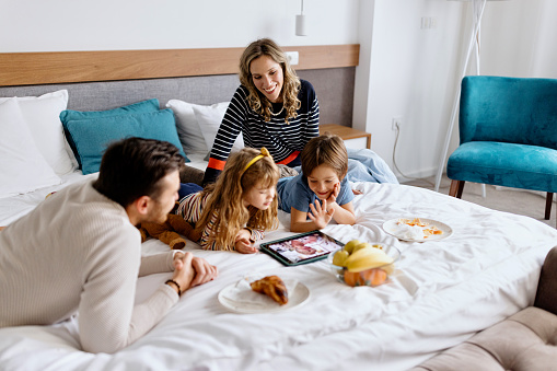 Happy family using digital tablet for video call with family while on vacation in a hotel