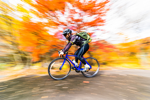 A slow shutter image of a cyclist riding down hill at speed during autumn in North Japan.