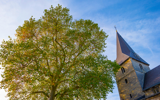 Tower of an ancient church in bright sunlight in a cloudy sky in autumn, Voeren, Limburg, Belgium, November, 2022